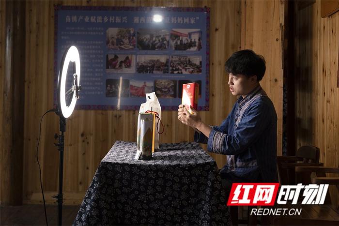施康通过直播带货推销十八洞村的农产品。