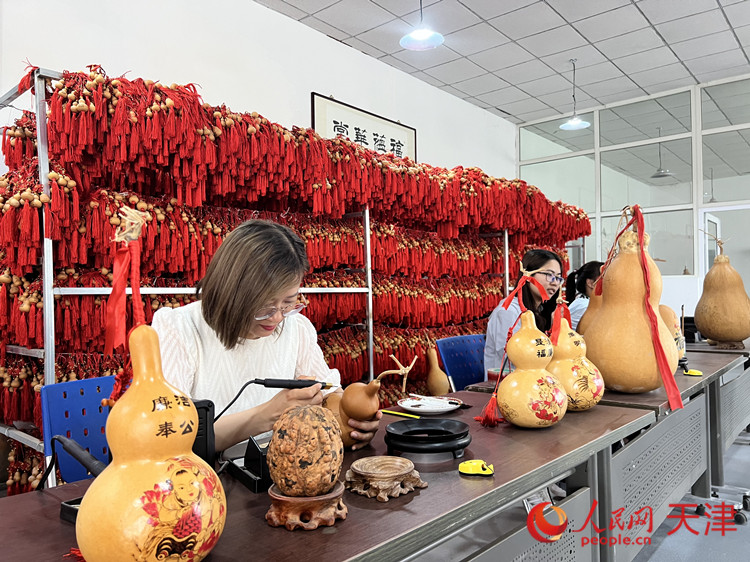 在大杜庄村葫芦加工体验馆，朱娜正在教学生们在葫芦上创作电烙画。人民网记者 孙翼飞摄